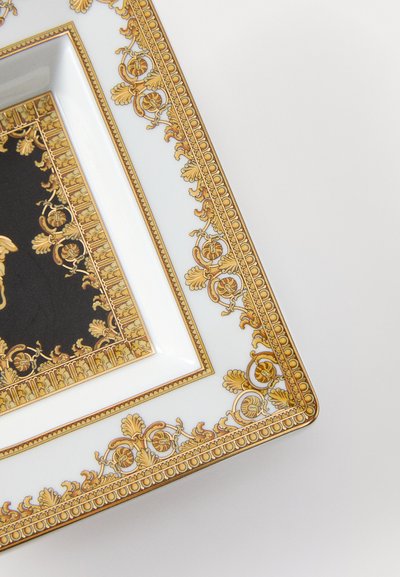 Obdĺžnikový porcelánový tanier s bielym základom, zložitým zlatým kvetinovým vzorom pozdĺž okrajov a čiernym dizajnom v strede.