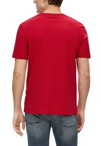 Rode T-shirt met korte mouwen en ronde hals, gemaakt van katoen. Gladde textuur, standaard pasvorm, achterkant gezien. Gecombineerd met blauwe spijkerbroek.