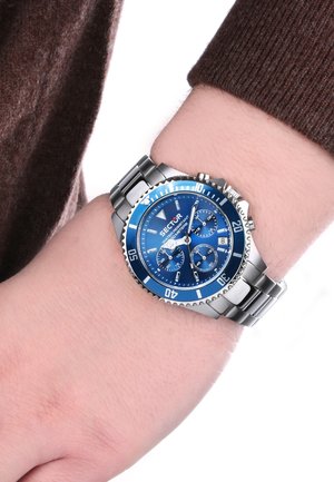 Orologio da polso con bracciale in argento, dotato di un quadrante blu, contrassegnato da indici delle ore bianchi e subquadranti, caratterizzato da una lunetta blu texturizzata e da una cassa in acciaio inox.