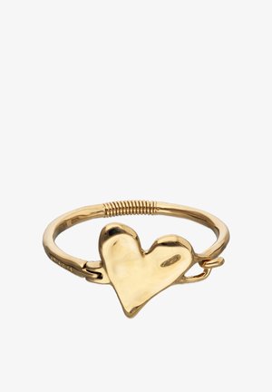 Bracelet en métal doré avec un grand pendentif en forme de cœur asymétrique et un détail côtelé sur le bracelet.