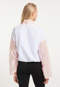 Hvid cropped jakke med iriserende lyserøde ærmer, elastisk kant og høj krave. Glat materiale med en let, skinnende tekstur.