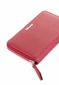 Red leather wallet with textured surface, zip closure, and silver hardware. Brand logo displayed on the front. Compact rectangular shape.