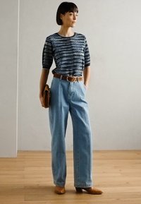 Stripet t-skjorte med korte ermer i marineblått og hvitt, kombinert med lyseblå høyhårede jeans og brune skinnhøye støvler. Akkompagnert med et belte.