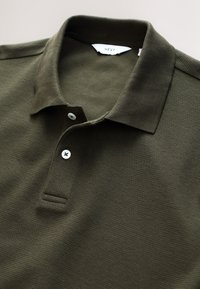 Maslinasto zelena polo majica od teksturiranog tkanja, s klasičnim ovratnikom, kratkim rukavima, tri gumba na prednjoj strani i rebrastim rubovima.