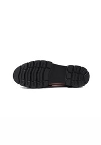 Sole di scarpa in gomma nera con un design a contrasto caratterizzato da scanalature e rilievi per una maggiore aderenza. Sezione centrale liscia con punta arrotondata.