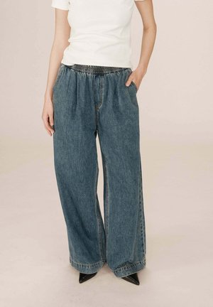 Pantalons en denim à jambes larges en coton bleu avec une taille élastique. Comprend des poches latérales et des détails de couture visibles.