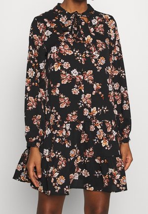 Das Blumen Kleid verfügt über lange Ärmel, einen Kragen mit einer Schleife und einen gestuften Saum. Die Farben umfassen Schwarz mit rosa, weißen und orangenen Blumenmustern.