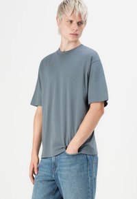 Grå kortermet t-skjorte i myk stoff med rund hals, kombinert med lyseblå denimjeans som har en avslappet passform og uformelt design.