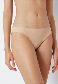 Bas de bikini beige sans couture au design taille basse, texture lisse et minimalisme dans les coutures, conçu pour le confort et un ajustement discret.