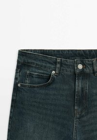 Dark blue denim jeans featuring a straight cut, a buttoned fly, five-pocket design, and contrasting stitching details.