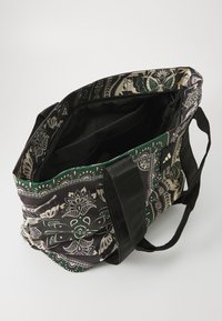 Tote bag made of fabric with a floral and paisley pattern in green, cream, and black. Features black handles and a spacious interior.