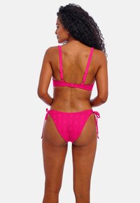 Roze bikini-set met een gestructureerde stof in een diamantpatroon. De bovenkant heeft verstelbare bandjes en een sluiting; de onderkant heeft zijveters.