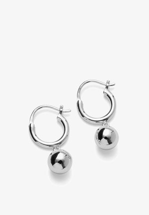 Boucles d'oreilles anneaux en argent avec pendantifs ronds et lisses en forme de boule suspendus à chaque anneau, présentées sur un fond blanc.