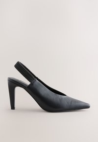 Scarpa slingback in pelle nera con punta affilata, caratterizzata da un cinturino elastico testurizzato e un tacco alto e affusolato. Superficie liscia, design minimalista.