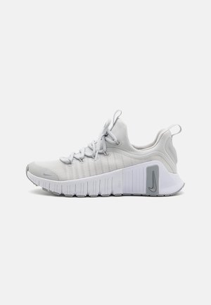 Chaussure de sport gris clair avec une tige en mesh respirant, des détails texturés sur les côtés, une semelle flexible et un contrefort de talon proéminent arborant un logo.