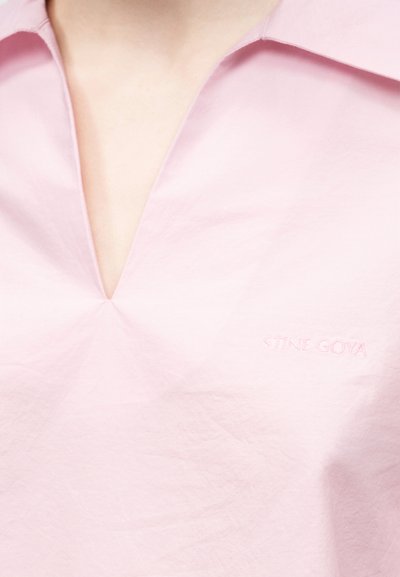 Világos rózsaszín galléros ing mély V-nyakkivágással és finom "STINE GOYA" hímzéssel a jobb mellrészen.
