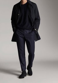 Black lightweight trench coat, navy sweater, tailored dark trousers, and black ankle boots. Smooth textures and classic design.