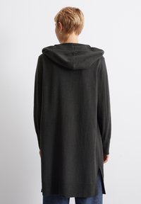 Hettegenser i mørkegrått, laget av myk stoff. Har en lang, avslappet passform med sidesliss og ribbede mansjetter og hem. 