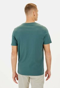 Kortærmet T-shirt i teal, lavet af blødt bomuld, med en rund halsudskæring og en glat overflade. Bagansigtet viser et ensfarvet design.