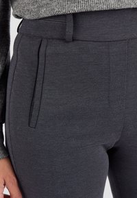 Donkergrijze op maat gemaakte broek van textuurstof, met een vlakke voorkant, twee voorplooien en een gladde tailleband.