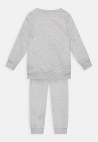 Hellgraues Baumwolle-Loungewear-Set mit einem langärmeligen Oberteil und schmal zulaufenden Hosen. Rippbündchen und Saum sorgen für zusätzliche Textur. Keine Muster.