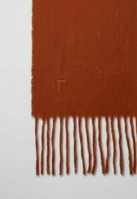 Pomarańczowy szalik o miękkiej fakturze, z frędzlami na brzegach i subtelnym wyszywanym logo na jednym końcu.
