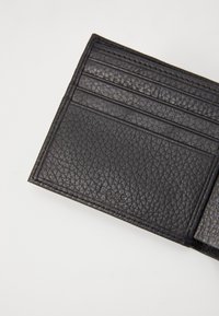 Black leather wallet with a textured finish. Features multiple card slots and embossed logo detail. Compact, rectangular shape.