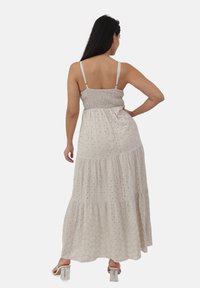 Abito maxi in crema chiaro con corpetto arricciato, spalline regolabili, design a strati e delicati dettagli a occhiello. Vestibilità standard.