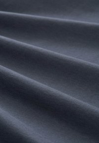 Tela gris oscuro con una textura suave, con suaves pliegues y arrugas que crean un sutil juego de luz y sombra.