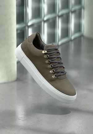 Brown leather sneaker with gray laces and gold hardware accents. Features a white rubber sole and textured detailing on the upper.