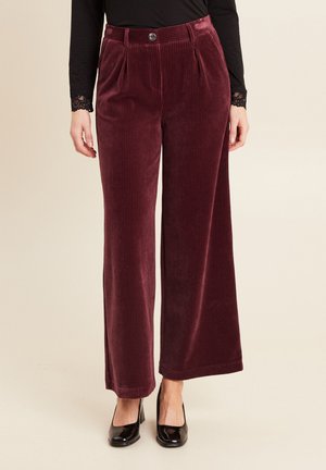 Bordeaux brede corduroy broeken met plooien, voorzien van een knoopsluiting en textuur, gecombineerd met zwarte schoenen.