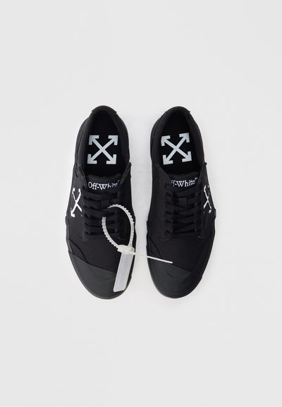 Sneaker nere in tela con suole in gomma, logo bianco e un laccio trasparente. Presentano lacci piatti e un design a bassa cima.