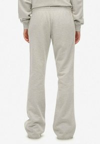 Light gray, sweatpants with a relaxed fit and flared legs. Made of soft fabric with an elastic waistband and simple stitching details.