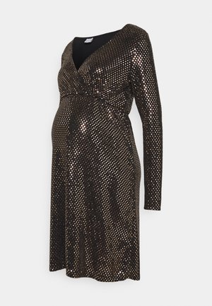 Robe de maternité noire à manches longues, col en V, avec un motif de pois métalliques dorés, conçue pour s'adapter et s'étirer sur un ventre de femme enceinte.