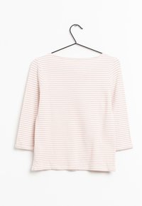 Chemise à manches longues rayée rose et blanche suspendue à un cintre en métal noir sur un fond blanc.
