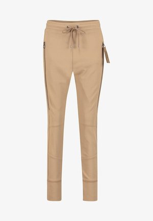 Pantalon beige slim avec taille à cordon de serrage à l'avant, fermetures éclair verticales sur les côtés et détails cousus au niveau des genoux, présenté sur un fond blanc.
