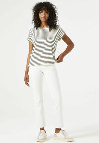 Camiseta de rayas blancas y negras de manga corta, combinada con pantalones rectos blancos y zapatillas claras. Diseño casual y sencillo.