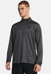 Dunkelgrauer Viertelreißverschluss-Pullover aus leichtem, strukturiertem Stoff. Mit langen Ärmeln und einem kleinen schwarzen Logo auf der Brust.