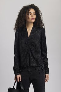 Blusa nera a maniche lunghe con scollatura a V e arricciature frontali, caratterizzata da un motivo testurizzato e dettagli di perline all'orlo, abbinata a jeans neri.
