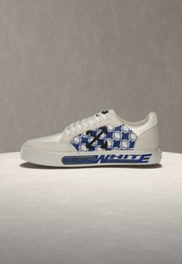 Άσπρο sneaker χαμηλής κορυφής με μπλε πλαϊνή επιφάνεια με σχέδιο, μαύρο λογότυπο βέλους και κείμενο "OFF-WHITE" σε μπλε στο πλάι της σόλας.