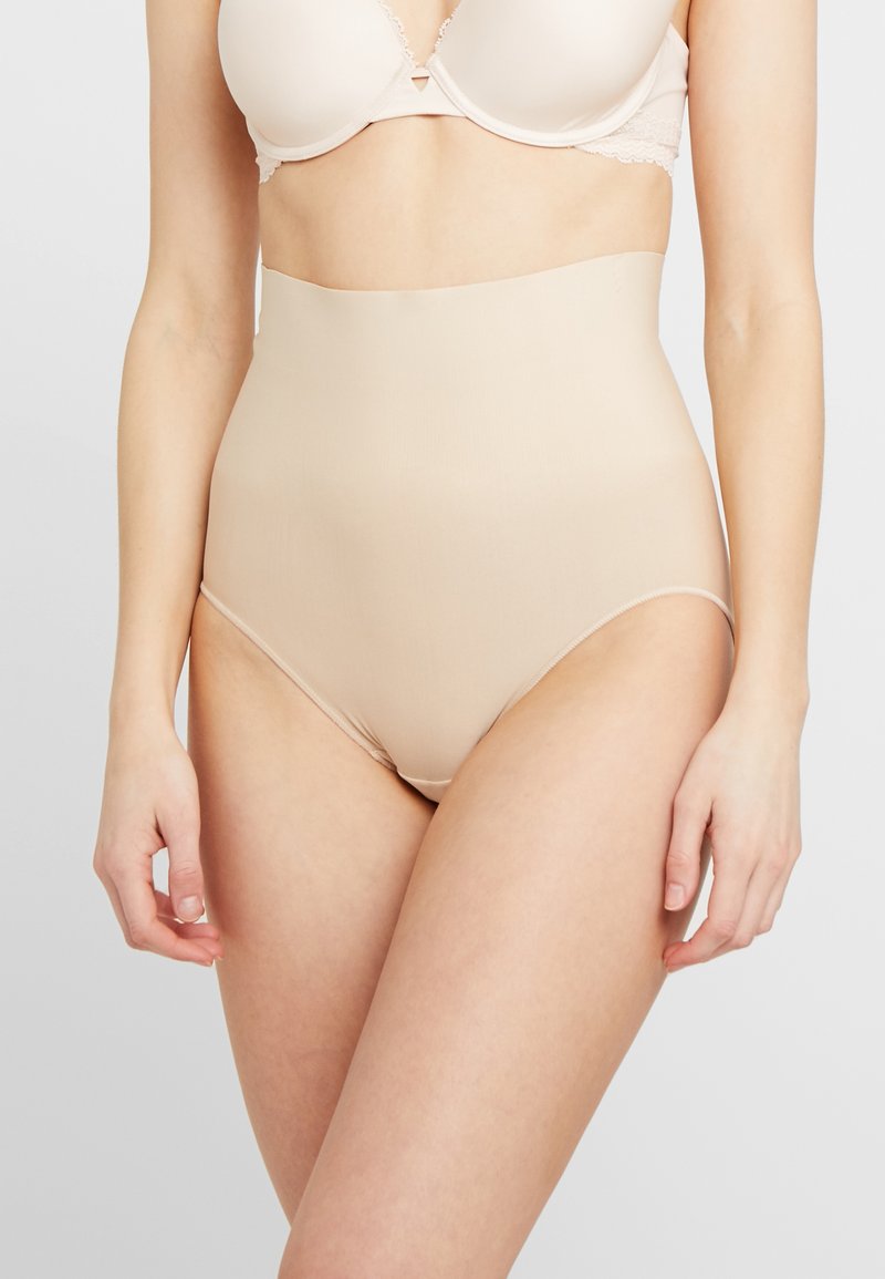 Høytlivd nude shapewear laget av glatt, elastisk stoff. Sømløst design med en myk tekstur som gir dekning og støtte.
