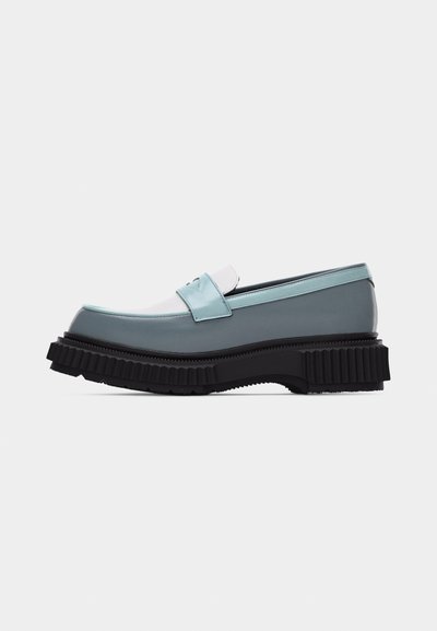 Εμφάνιση πλατιού μοκασίνι με παχιά μαύρη ραβδωτή σόλα, γκρι σώμα, λουράκι ανοιχτού γαλάζιου και λεπτομέρεια λευκής γλώσσας, σε πλάγια όψη σε λευκό φόντο.
