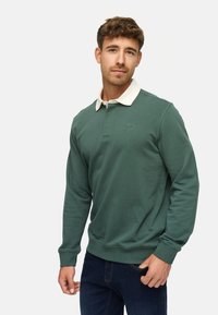 Groene pullover sweatshirt met een witte kraag, lange mouwen en ribbelmanchetten. Wordt gekenmerkt door een klein logo op de borst. Zachte textuur.
