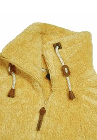 Collo in morbido pile giallo con zip e cordini bianchi dotati di fermi e dettagli in pelle marrone.