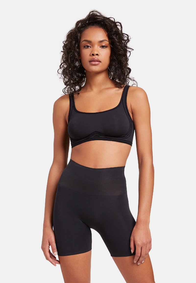 Zwarte sport-bralette met brede banden en middellange fietsshorts. Gladde textuur, minimale naden, ontworpen voor comfort en beweging.