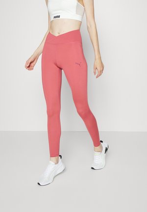 Leggings rosa con una vita alta, realizzati in materiale elastico. Presentano un sottile logo Puma sulla coscia e un design liscio e aderente.