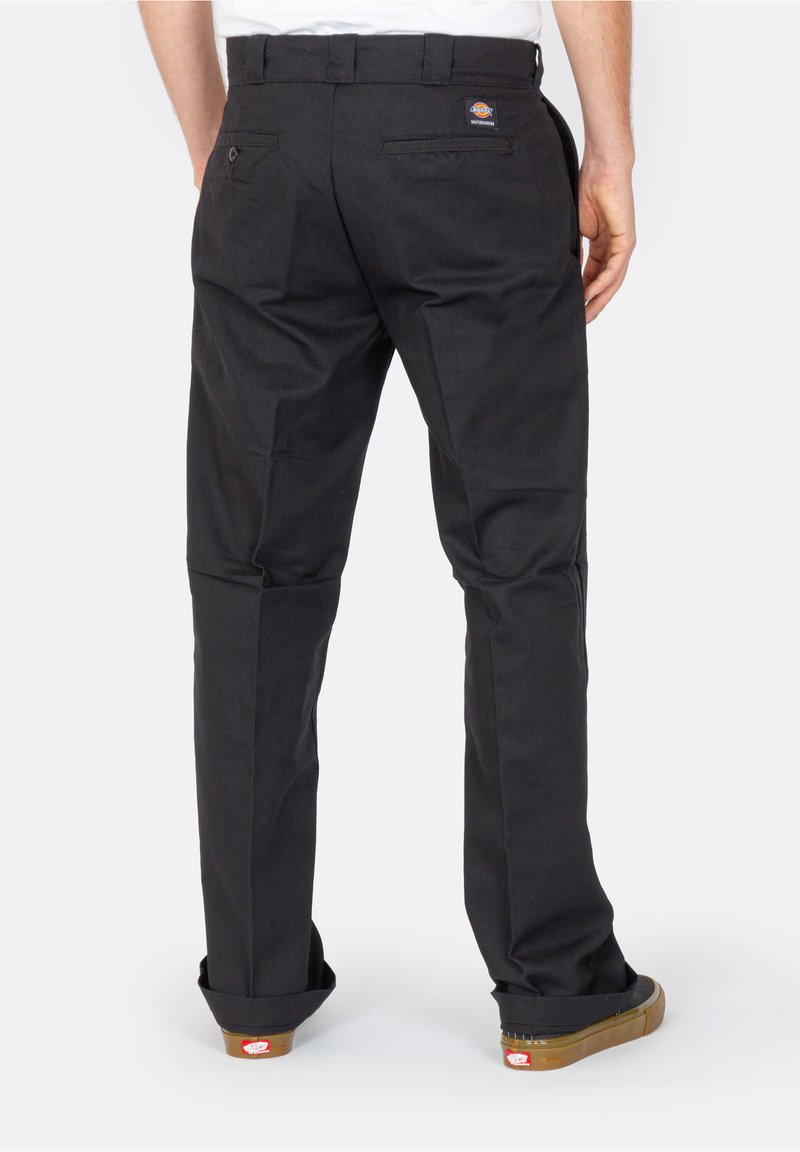Schwarze Hose aus robustem Stoff, mit geradem Bein, zwei Gesäßtaschen und aufgeschlagenen Säumen. Sichtbares Markenetikett über der rechten Tasche.