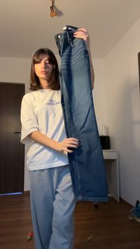 Blue denim jeans with a straight-leg design, high waist, and subtle fading. Features a classic button and zipper closure, held up by a model.