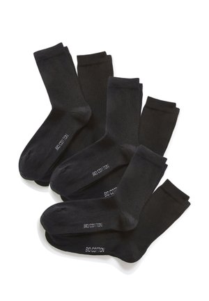 Seis pares de calcetines negros de longitud media dispuestos superpuestos, cada uno con la etiqueta "ALGODÓN ORGÁNICO" en la suela con texto blanco.