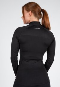 Zwart sportshirt met lange mouwen, hoge kraag, slim-fit en een soepele textuur. "GORILLA WEAR" logo op de achterkant nabij de kraag.